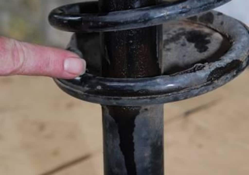 Hình ảnh đang mô tả phuộc ô tô bị rò rỉ dầu bám bụi đen