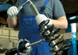 Kỹ thuật viên kiểm tra cụm phuộc và lò xo giảm xóc xe Ford Focus trong xưởng sửa chữa